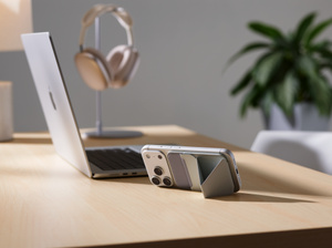 Moft MagSafe Wallet Stand, back exterior, iPhone attached to Moft wallet stand, both in landscape orientation, placed on a desk next to a MacBook