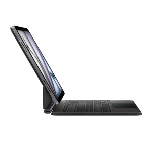 Parte lateral de un Magic Keyboard negro con aluminio negro para el iPad Air, con teclas negras, puerto USB-C en la parte inferior izquierda cerca del pliegue, diseño flotante y un iPad Air conectado en posición horizontal con la pantalla inclinada hacia atrás