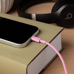Beats USB-C to USB-C Woven Cable in Power Pink plugged into iPhone.