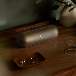 Front angled view of the Beats Pill Bluetooth® Speaker in Champagne Gold with “b” logo on the front grill. 
