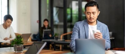 A man in a suit sitting at a table with a laptop.