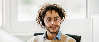 A person with curly hair wearing a headset.