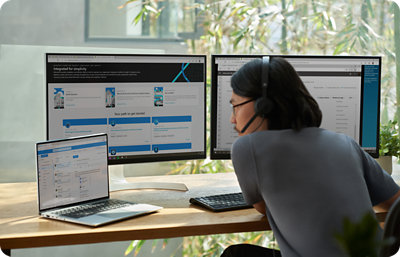 Person with headset working on a laptop and two monitors, displaying various software interfaces