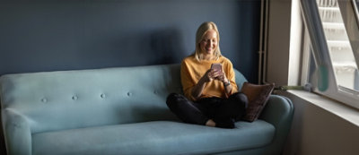 A woman sitting on a couch looking at her phone.